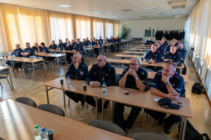 Policjanci siedzą w ławkach na sali konferencyjnej