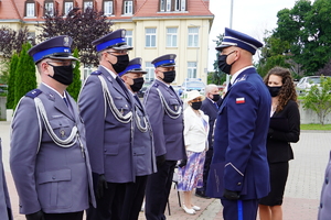Komendant Wojewódzki stoi przed policjantem i trzyma w ręku teczkę