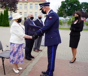 Komendant Wojewódzki gratuluje i przekazuje teczkę starszej kobiecie