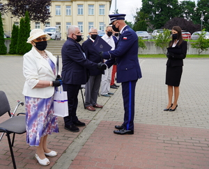 Komendant Wojewódzki gratuluje i przekazuje teczkę starszemu mężczyźnie