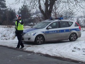 Policjant zimą przy radiowozie.