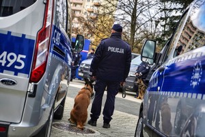 Policjant stojący pomiedzy radiowozami.