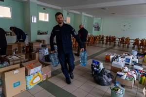 Policjant niesie baniaki z pitną wodą