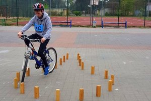 dziecko pokonuje na rowerze przeszkodę. Omija małe drewniane pachołki