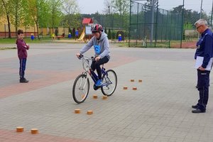 policjant patrzy jak dziecko omija na rowerze przeszkodę