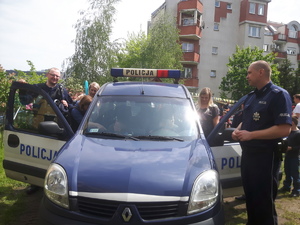 Teren przyszkolny. Policjanci i dzieci przy radiowozie.