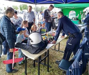 Teren wystawy &quot;AIR FAIR 2019&quot; . Stoisko policyjne (namiot). Policjant rozmawia z dziećmi w obecności ich opiekunów.