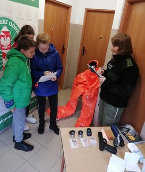 Pomieszczenie w budynku ośrodka. Zawodnicy podczas zadania, które ocenia funkcjonariusz Urzędu Celnego.