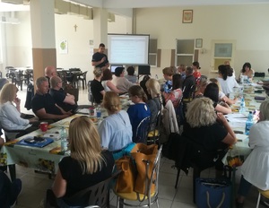 Sala szkolna. Grono pedagogiczne podczas prelekcji policjanta.