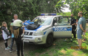 Uczestnicy Dnia Dziecka oglądają policyjny radiowóz oraz wyposażenie służbowe policjanta.