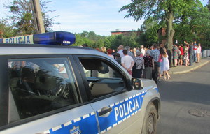Policjanci czuwają nad bezpieczeństwem uczestników marszu. Na pierwszym planie radiowóz policyjny.