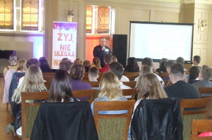 Sala konferencyjna. Prelekcja policjanta Komendy Miejskiej Policji w Bydgoszczy skierowana do uczestników forum.