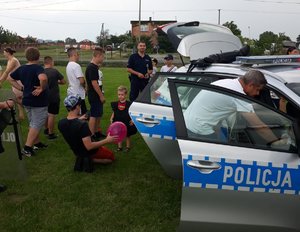 Dzieci i dorośli oglądają radiowóz podczas festynu.