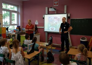 Policjanci na zajęciach z uczniami przeprowadzonych w klasie szkolnej.