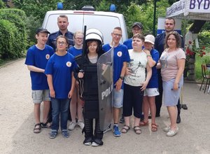 Zdjęcie wspólne na tle radiowozu. Stoją policjanci, uczniowie i ich opiekunowie.