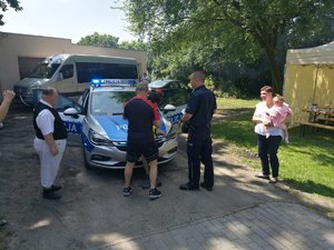 Podopieczni ośrodka oglądają radiowóz policyjny. Czuwają nad tym policjanci.