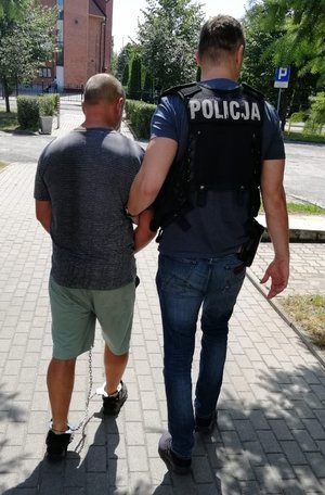 Policjant prowadzi zatrzymanego.