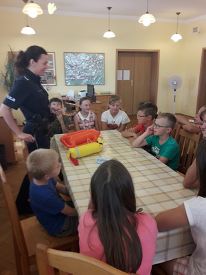 Policjantka podczas zajęć w sali prezentuje przedmioty służące do ratowania ludzi w wodzie.