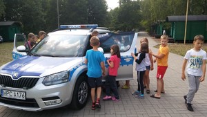 Policjant pokazuje dzieciom policyjny radiowóz.