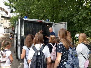 Goście oglądają policyjny radiowóz. Towarzyszy im policjant.