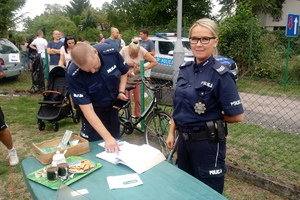 policjanci stoją przy stoisku na festynie