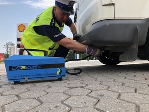 Policjant podłącza maszynę sprawdzającą ilość spali do rury wydechowej