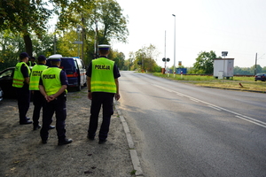 Policjanci i pracownicy SOK stojący przed przejazdem kolejowym.