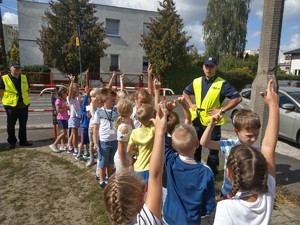 Policjanci rozmawiają z dziećmi przy przejściu dla pieszych.