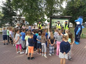 Policjanci wraz z polfinkiem rozmawiają z dziećmi.