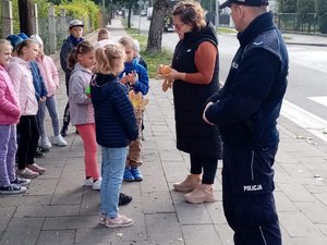 Prowadzący spotkanie rozdają dzieciom odblaski.