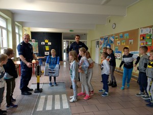 Dzieci pod okiem policjantów ćwiczą przechodzenie przez jezdnię z wykorzystaniem miasteczka ruchu drogowego.