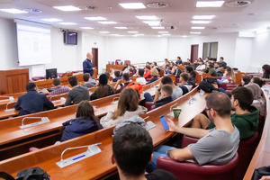 Mł. asp. Rafał Wohlfeil rozmawia ze studentami w sali wykładowej uniwersytetu.