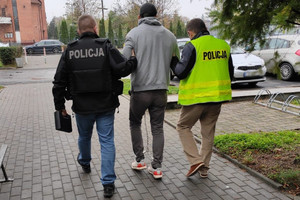 policjanci prowadzą zatrzymanego skutego kajdankami