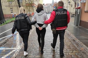 policjanci prowadzą zatrzymaną skutą kajdankami