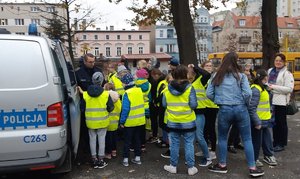 Policjant i wychowankowie przy radiowozie.