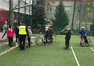 Policjant rozmawia z uczniami na boisku szkolnym.