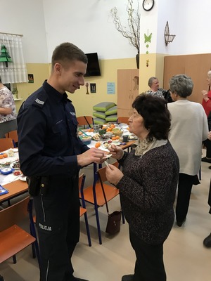 Policjant podczas z\składania życzeń seniorce.