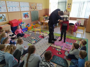 Policjant pokazuje elementy wyposażenia policjanta do służby podczas zabezpieczeń imprez masowych.