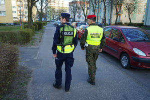 policjant z żandarmem idą chodnikiem i patrolują ulice