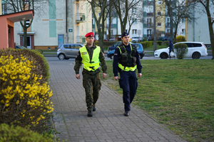 policjant z żandarmem idą chodnikiem i patrolują ulice