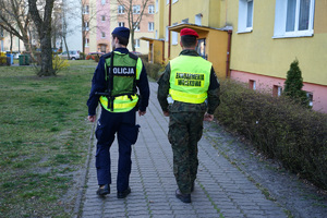 policjant z żandarmem idą chodnikiem i patrolują ulice