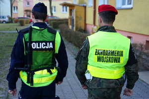 policjant z żandarmem idą chodnikiem i patrolują ulice