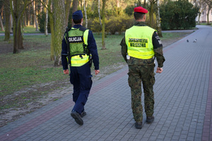 policjant z żandarmem idą chodnikiem i patrolują ulice