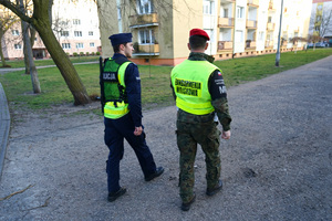 policjant z żandarmem idą chodnikiem i patrolują ulice