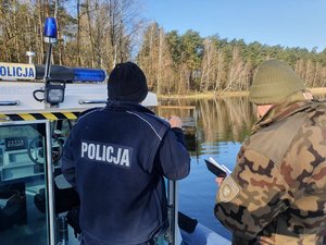 Policjant i funkcjonariusz Państwowej Straży Rybackiej podczas patrolu łodzią.