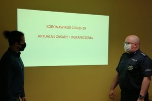 policjant omawia wyświetlane slajdy. Po przeciwnej stronie stoi tłumacz