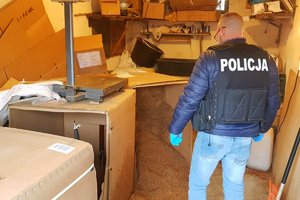 policjant stoi i patrzy na worki oraz kartony z tytoniem