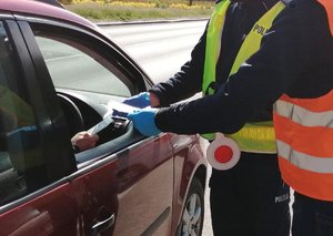 Policjant i przedstawiciel Bydgoskiego Zarządu Dróg Miejskich i Komunikacji Publicznej wręczają nagrodzonemu kierowcy upominek.