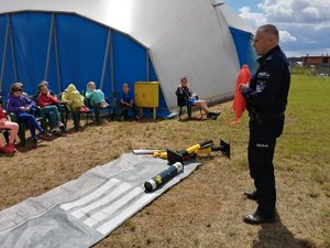 Policjant podczas spotkania prezentuje sprzęt ratowniczy używany nad wodą.