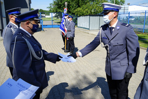 Komendant wręcza policjantowi rozkaz